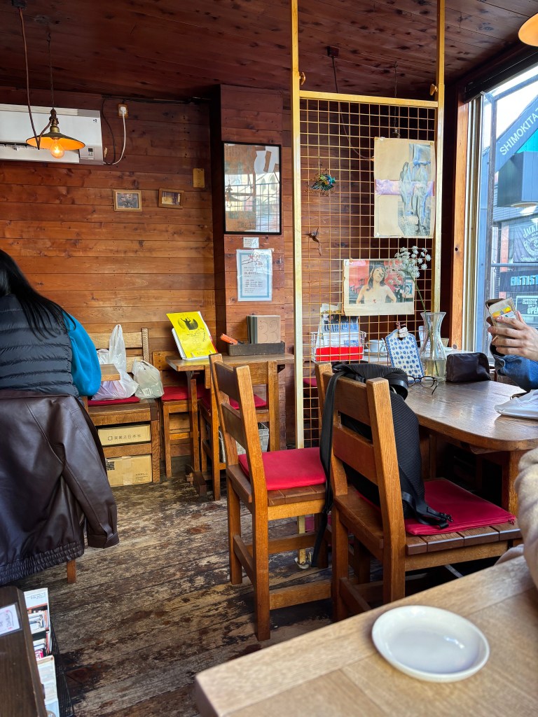Interior of a cozy kissaten in Shimokitazawa, showcasing wooden furniture, warm lighting, and decorative elements on the walls.